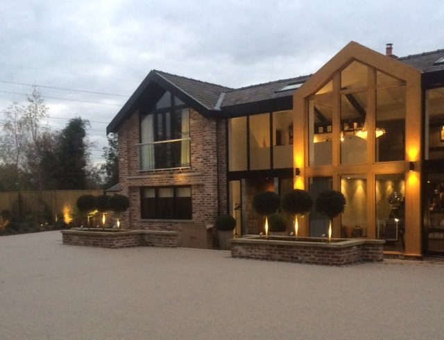 A lovely home light up in dusk with a yellow resin bound driveway.